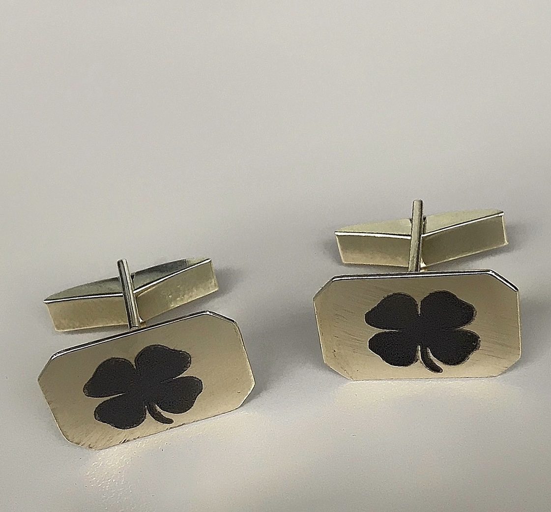 Square gold cufflinks engraved with a four leaf clover motif