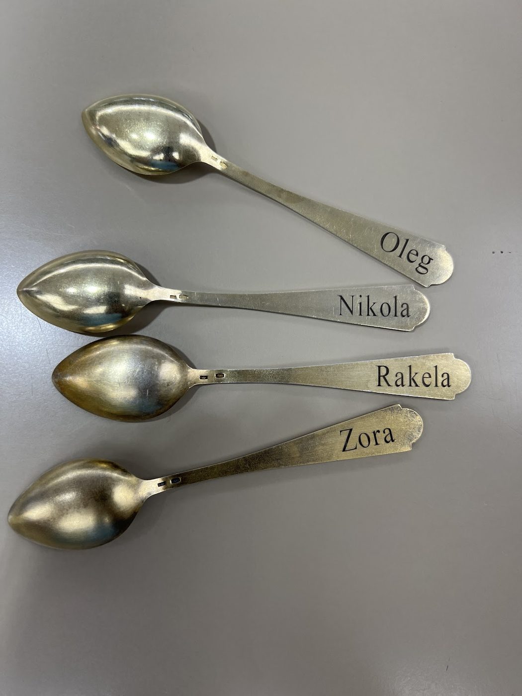 Four silver spoons each engraved with a different name