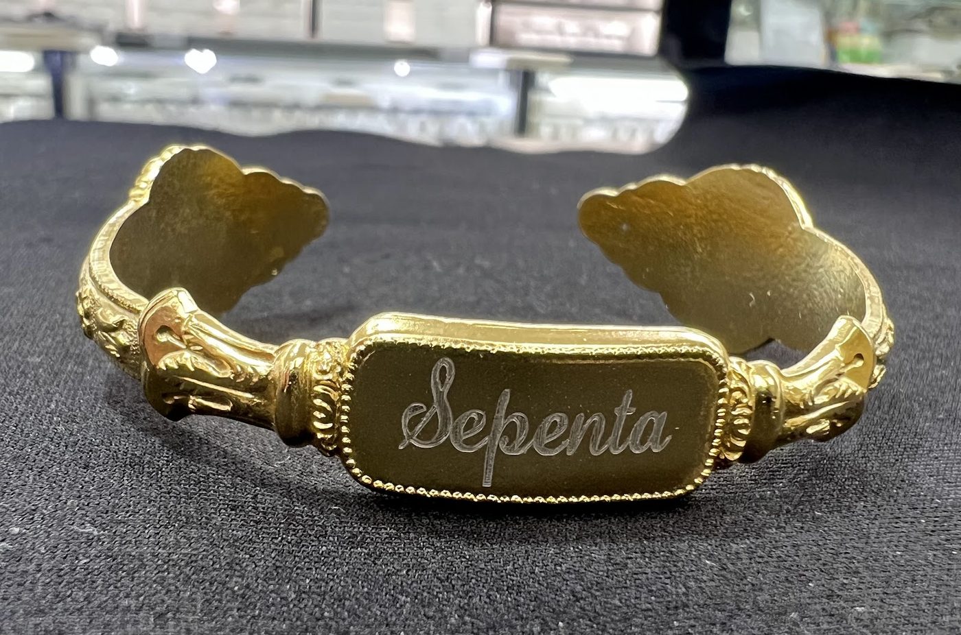 Gold bangle with a central plate engraved with a name