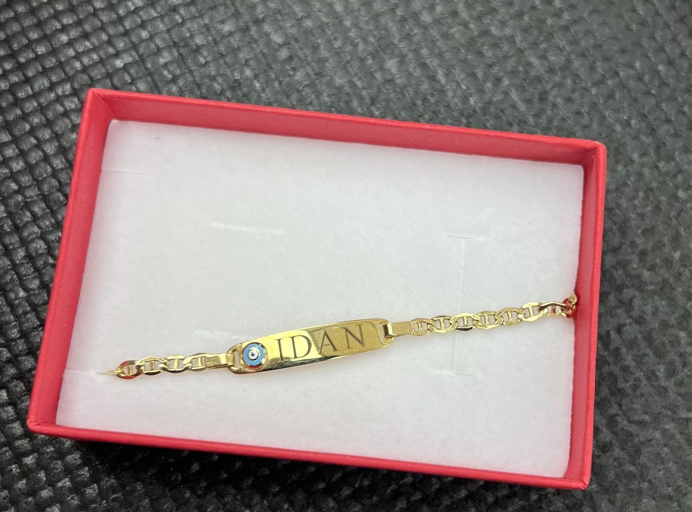 Slim gold identity bracelet presented in a red gift box