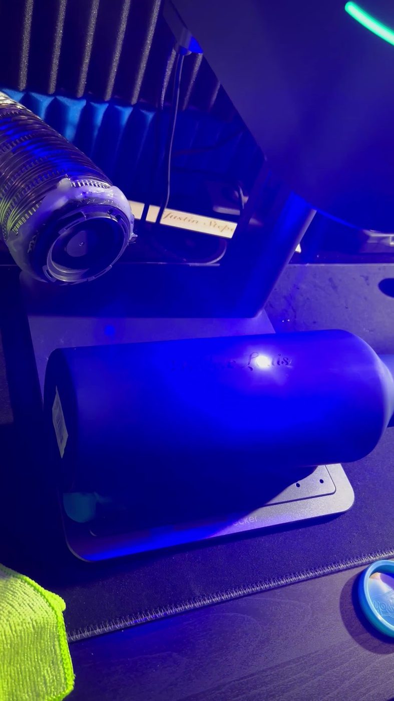A laser engraver marking a metal item, lit by the machine blue light