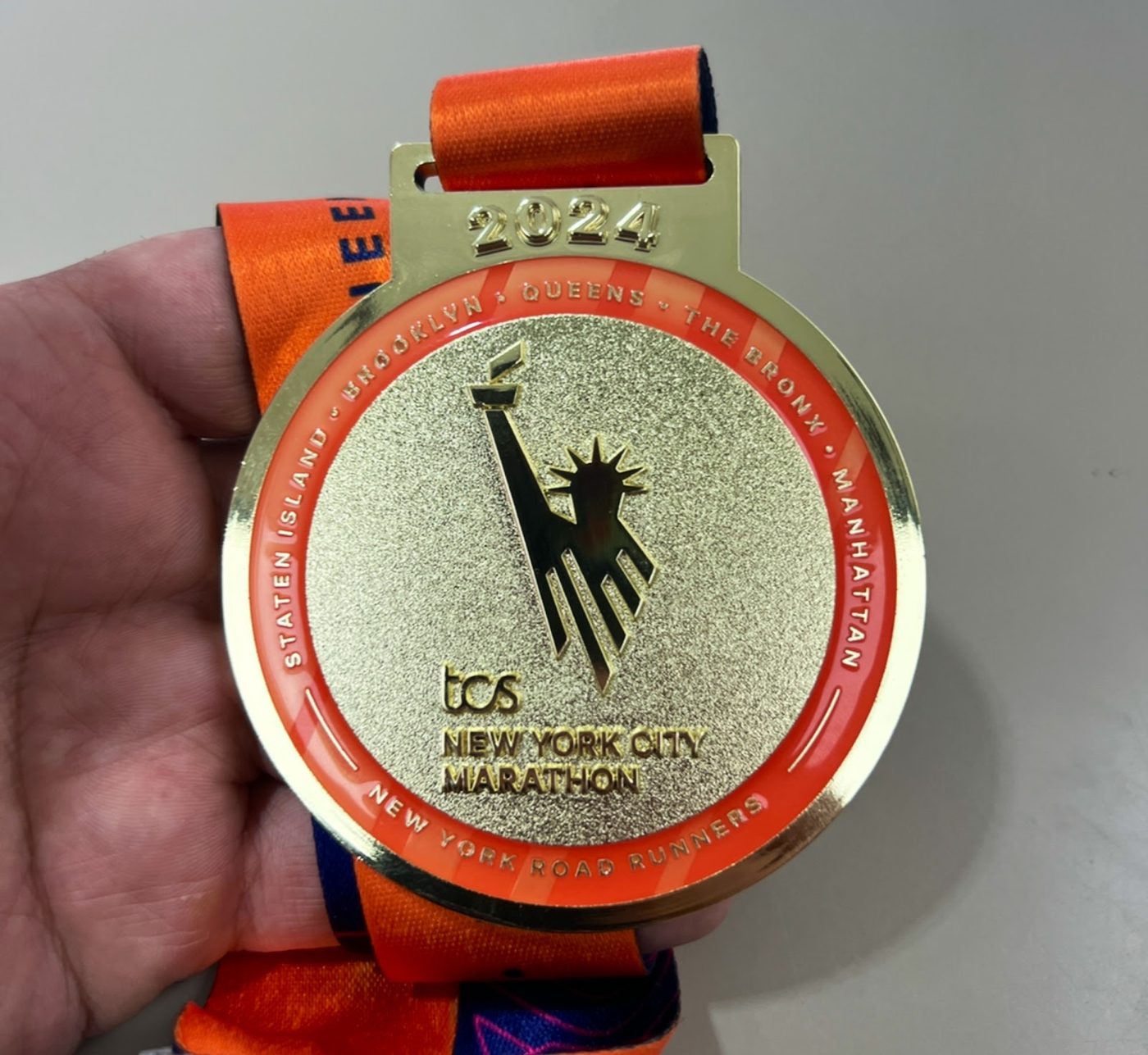 Gold TCS New York City Marathon finisher medal held in a hand