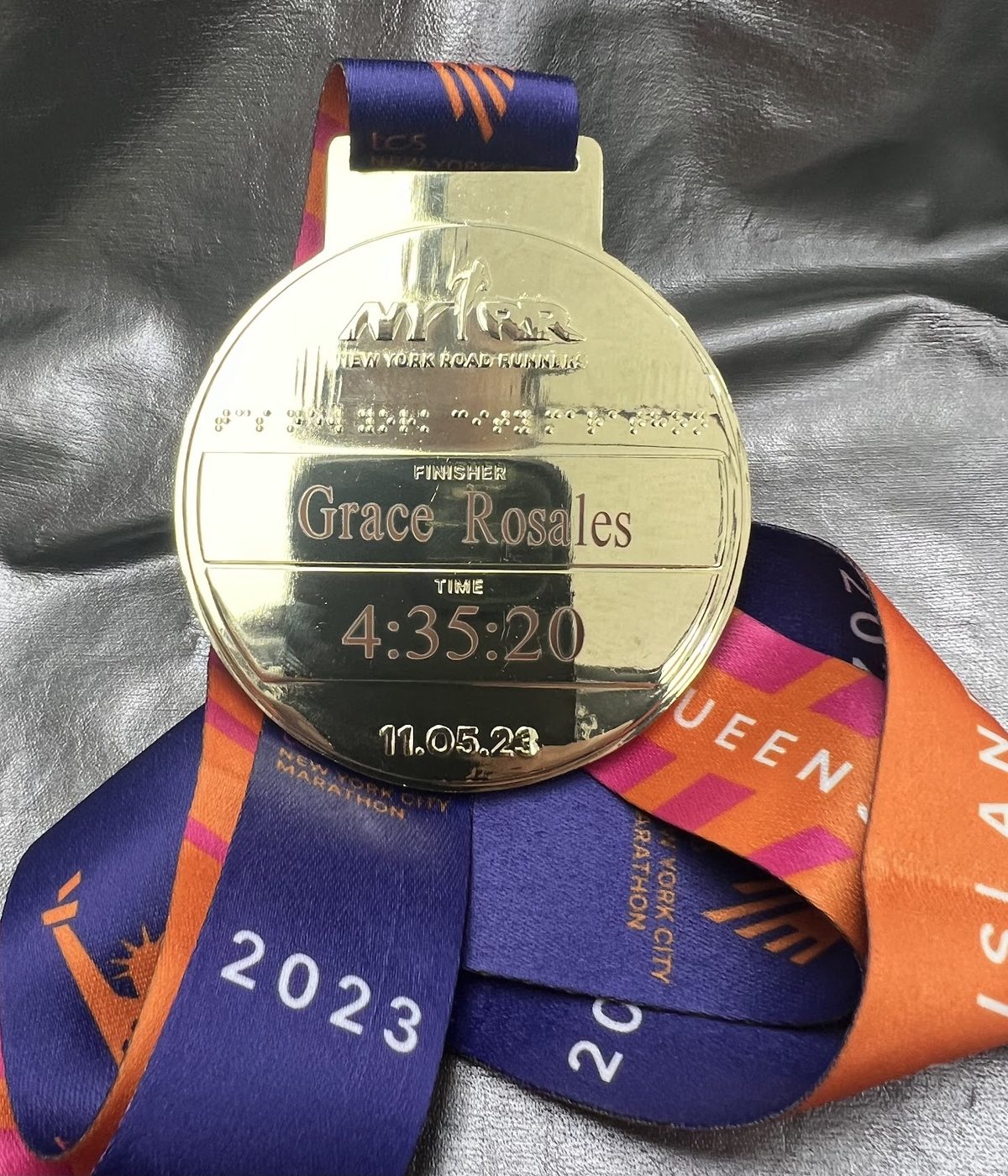 A stack of New York City Marathon medals engraved with finishing times