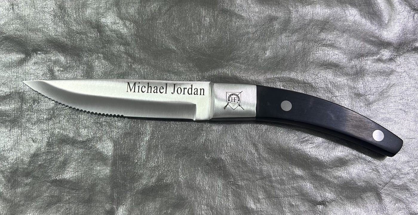 Stainless steak knife engraved with the name Michael Jordan beside a dark wooden handle