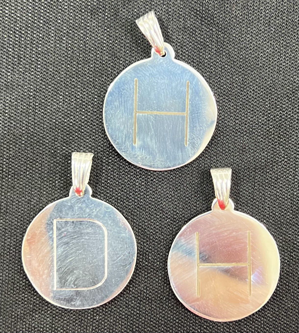 Three round pendants engraved with single letter monograms