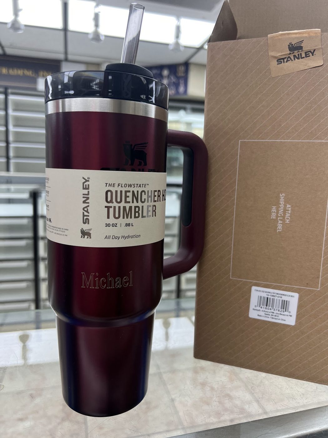 Red insulated tumbler engraved with a name beside its packaging