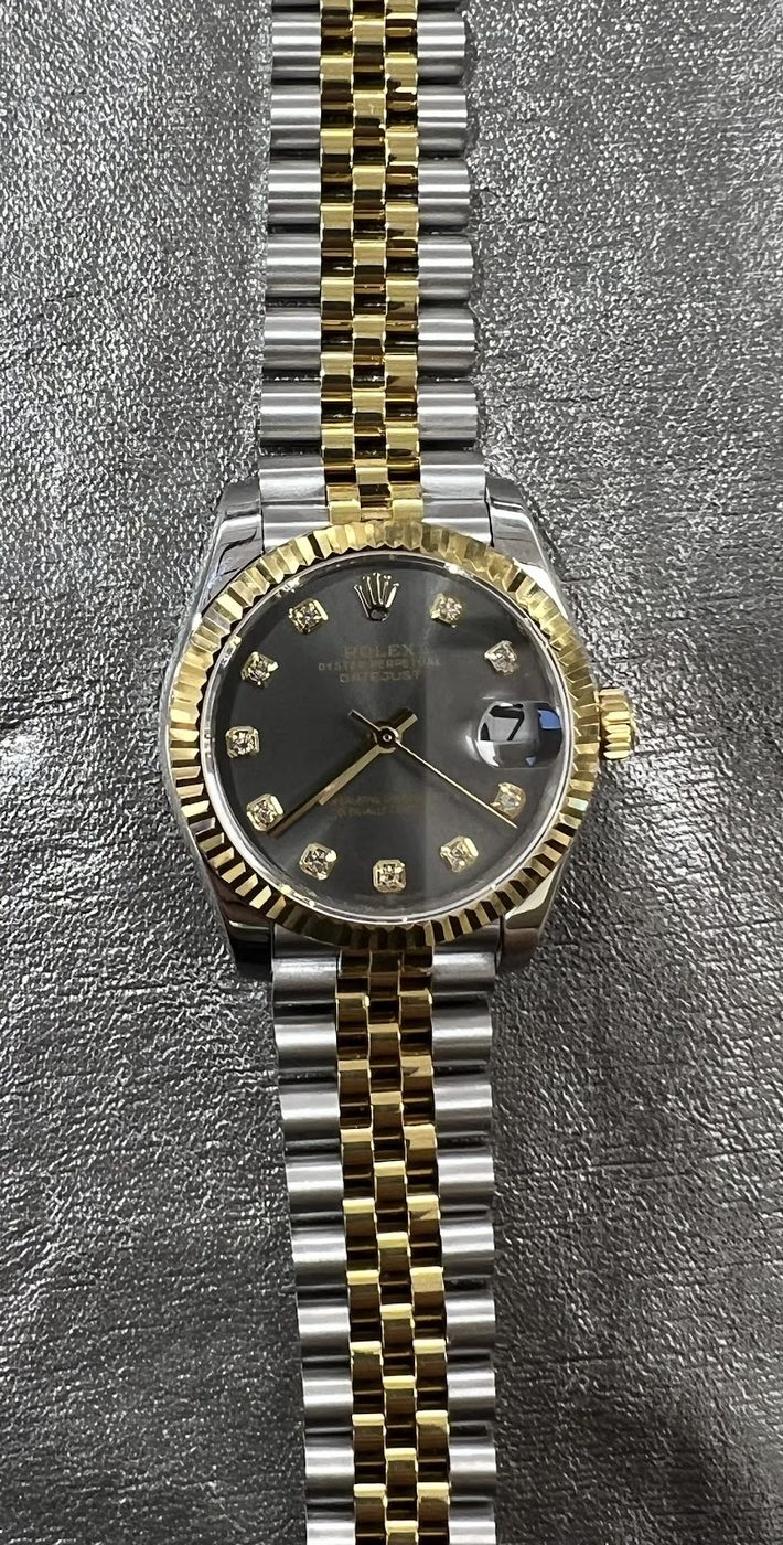 Two-tone Rolex Datejust with fluted bezel resting on a work surface