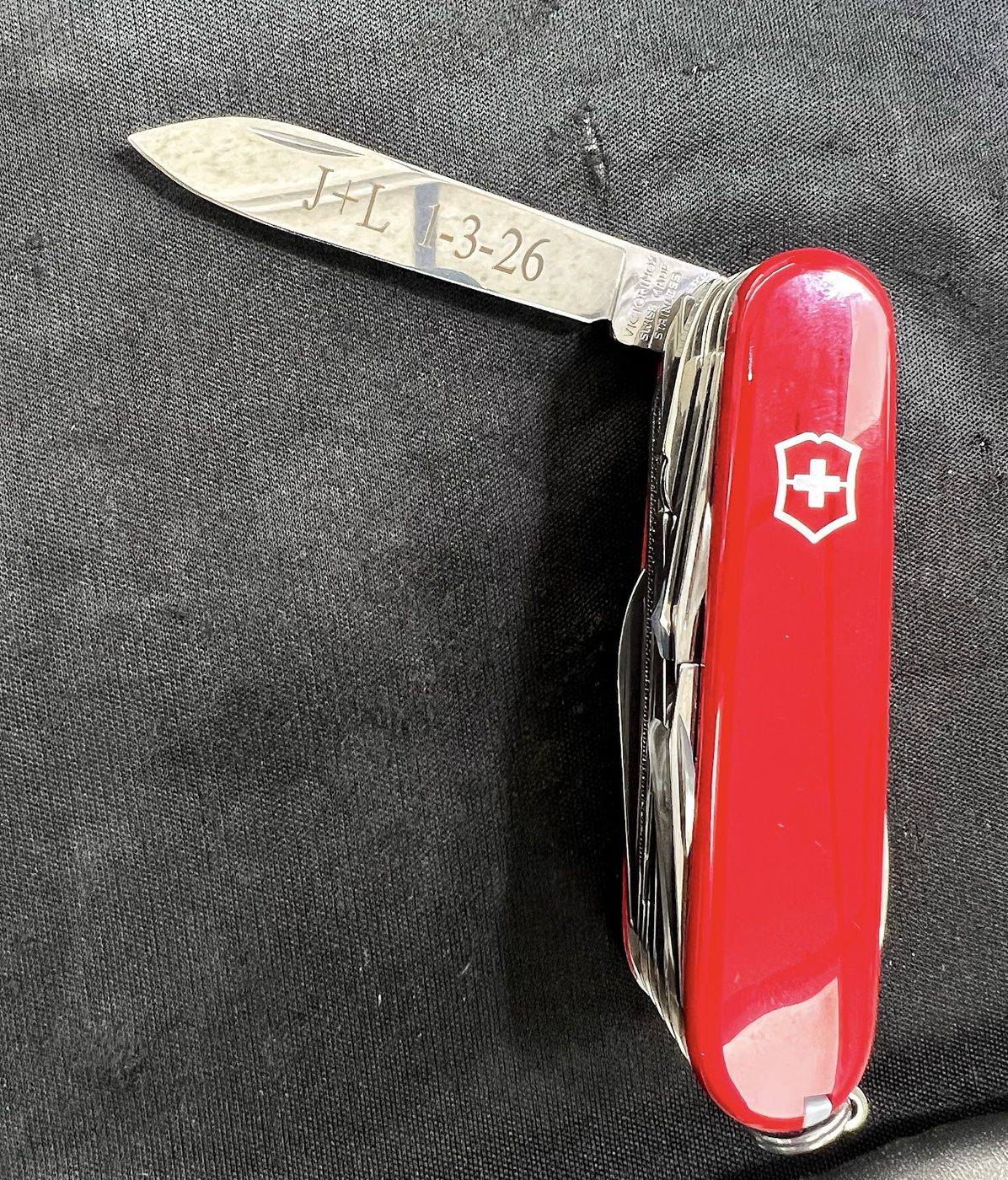 Red Victorinox Swiss Army knife engraved with initials and a date