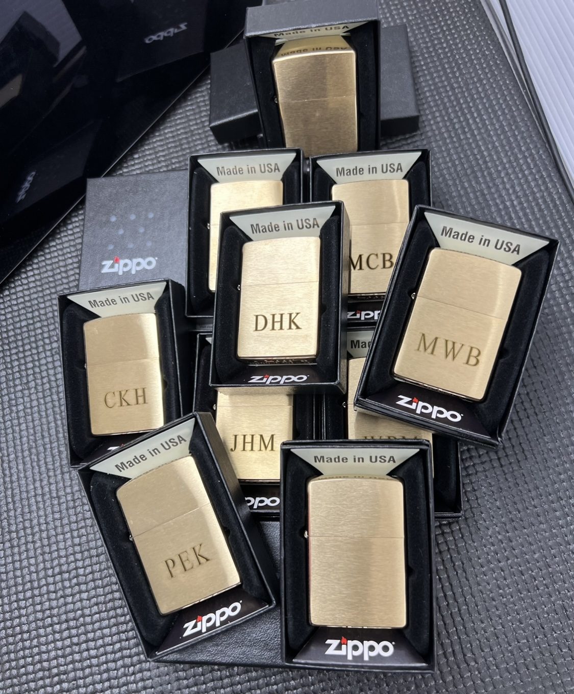 A batch of brass Zippo lighters engraved with different sets of initials